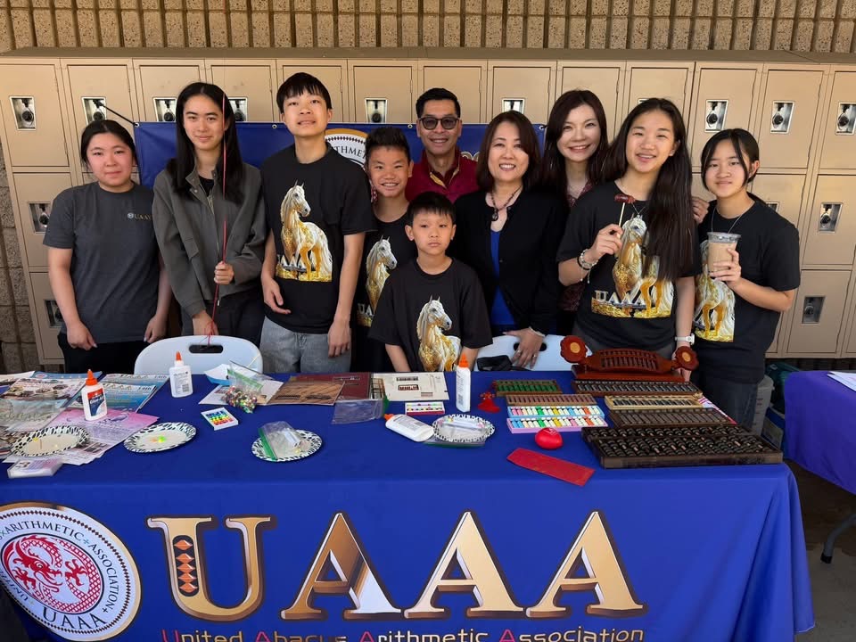 【教育】美国珠心算联合会(UAAA)的安秋玲老师带着几名孩子在活动摊位上向来宾介绍珠心算